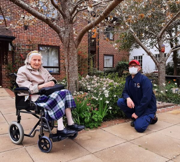 resident in wheelchair in garden with gardener
