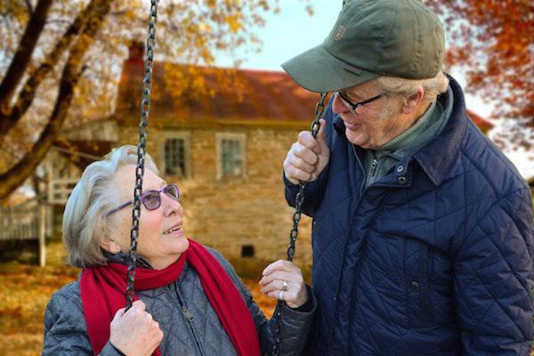 Couple looking at each other with one on a swing
